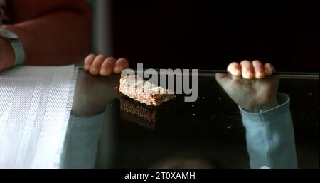 Child snacking bread and butter. Baby boy leaning on glass table grabbing food Stock Photo