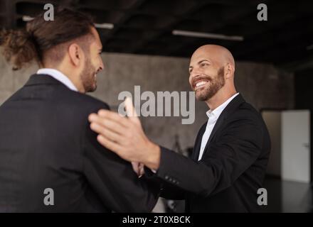 Businessman Greeting Young Colleague Celebrating Career Milestone In Modern Office Stock Photo