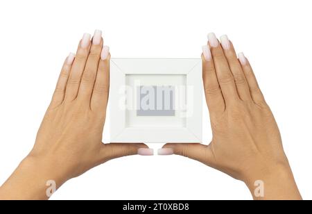 Adult female hands with long square ombre manicured nails, holding up an empty photoframe with borders. Isolated on a white background. Stock Photo