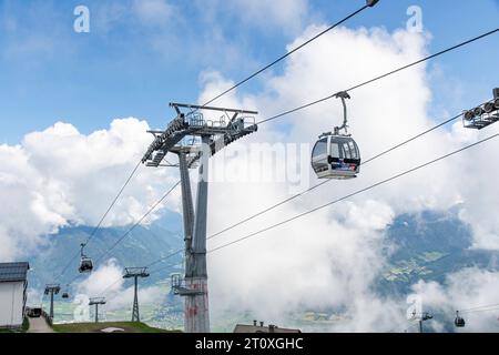 Kronplatz, Italy-June 14, 2023; View from summit of Kronplatz mountain with cable cars in front and surrounded by white clouds at high elevation and v Stock Photo