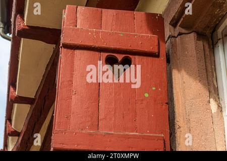detail of old red wooden shutter with hole in heart shape on half-timbered house in small city in south germany Stock Photo