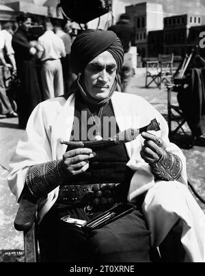 CONRAD VEIDT Candid Portrait taken on the set of THE THIEF OF BAGDAD 1940 examining a Persian dagger that he wears in the film. Directed by LUDWIG BERGER and MICHAEL POWELL Screenplay MILES MALLESON Costume Design JOHN ARMSTRONG, OLIVER MESSEL and MARCEL VERTES Music MIKLOS ROZSA  Alexander Korda Films/London Film Productions/United Artists Stock Photo