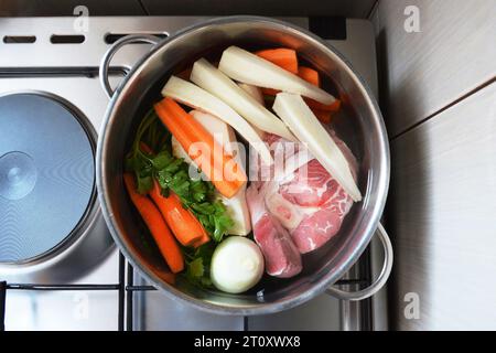 Ingredients for beef soup in pot. Meat, fresh vegetables and herbs prepared for cooking beef soup. Top view Stock Photo