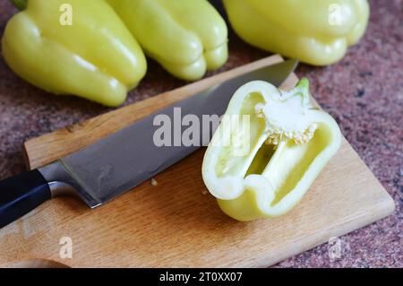 Yellow bell pepper cut in half on wooden cutting board Stock Photo