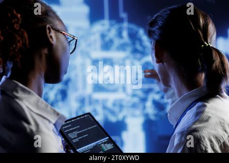 IT consultants brainstorm ways to use AI cognitive computing to extract usable information from complex data. High tech facility workers implement artificial intelligence to process inference datasets Stock Photo