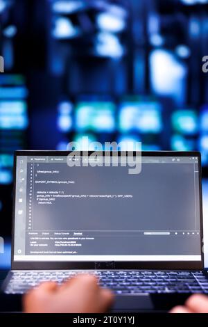Close up shot of developers updating server rigs, writing complex binary code scripts on laptop. Programmers using JavaScript, Java, and database programming to fortify cybersecurity in data center Stock Photo