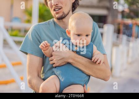 In a heartwarming outdoor scene, a caring dad and his baby share quality time, creating precious family memories amidst nature's beauty Stock Photo