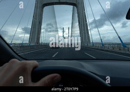 View from the driver's seat POV of the car on the Vasco da Gama bridge in Lisbon, on a cloudy day. Lisbon, Portugal Stock Photo