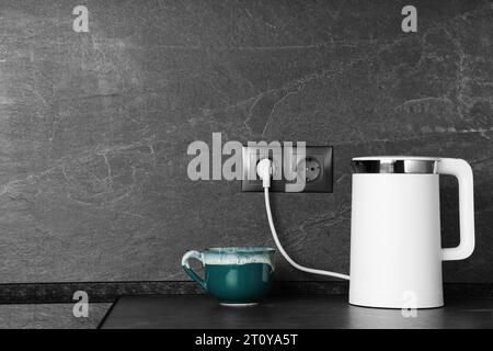 https://l450v.alamy.com/450v/2t0ya5t/electric-kettle-plugged-into-power-socket-on-dark-grey-wall-indoors-space-for-text-2t0ya5t.jpg