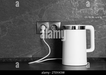 https://l450v.alamy.com/450v/2t0ya5w/electric-kettle-plugged-into-power-socket-on-dark-grey-wall-indoors-2t0ya5w.jpg