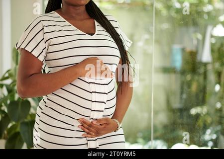 Cropped image of pregnant woman in striped dress touching her belly Stock Photo