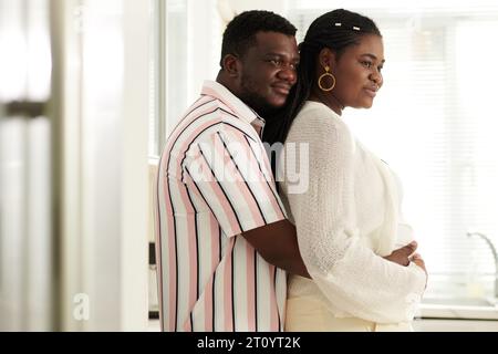 Happy man hugging his pregnant wife from behind Stock Photo