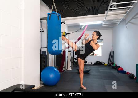 A Young woman exercises with a punching bag in a gym. Stock Photo