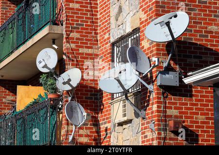 Multiple TV satellite dishes on the side of an apartment building in NYC. Dish network, DirecTV digital satellite broadcast antennas. Stock Photo