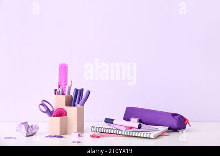 Holder with different stationery and notebooks on light desk Stock Photo