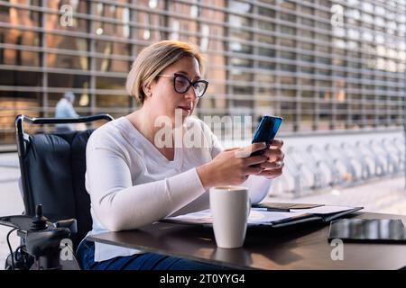 woman using wheelchair using mobile on a terrace Stock Photo
