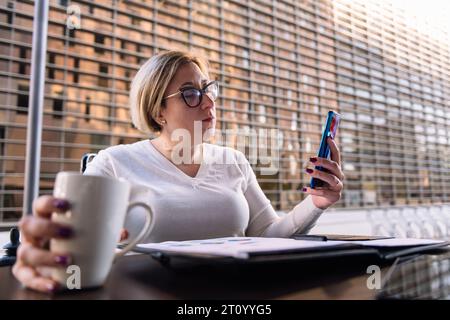 woman using mobile phone sitting on a terrace Stock Photo