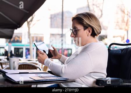 woman using wheelchair working with a tablet Stock Photo