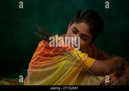 Portrait of woman looking at peacock feather holding in her hand Stock Photo