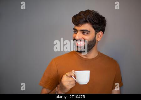 Portrait of cheerful man drinking tea against grey backgroiund Stock Photo