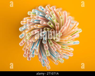 Overhead view of a group of colored straws forming a spiral on a yellow background. Stock Photo