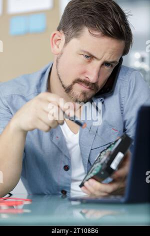 young technician working on broken computer Stock Photo