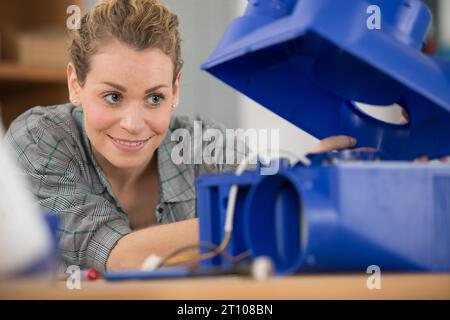 female maintenance engineer testing voltage with digital multimeter Stock Photo