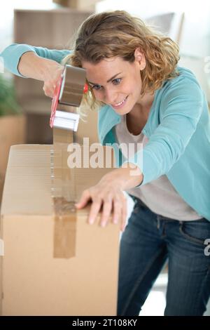 woman taping up a cardboard box Stock Photo
