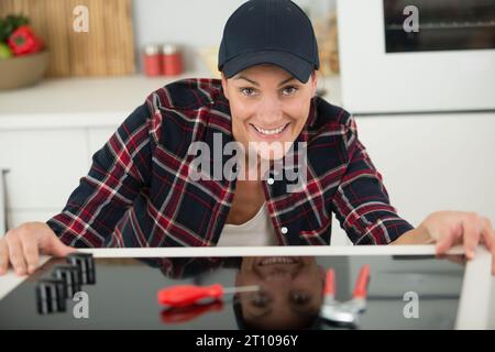 woman installing an induction hob in a kitchen Stock Photo