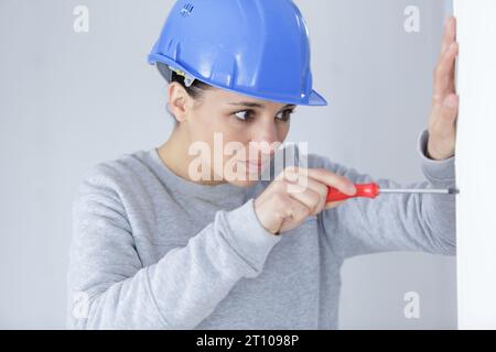 happy female builder with screwdriver fixing socket indoors Stock Photo