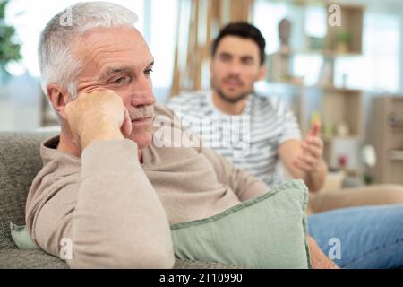 handsome man looking at sad senior dad Stock Photo