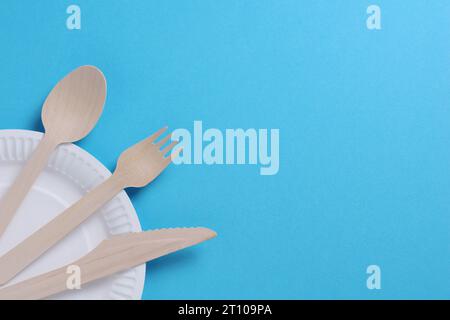 Wooden cutlery on a disposable paper plate on blue background, top view with copy space Stock Photo