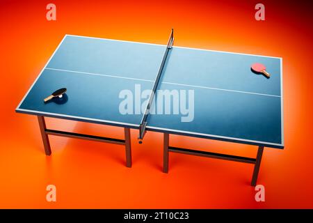 A professional setup of a blue table tennis table standing in an empty room with vibrant red flooring. Rackets and a ball are placed on the table, rea Stock Photo