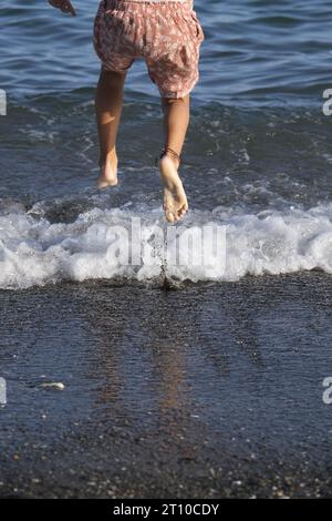 girl jumping on the shore contentedly playing autumn Stock Photo