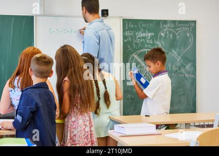 Male and female elementary students learning mathematics with teacher in classroom Stock Photo