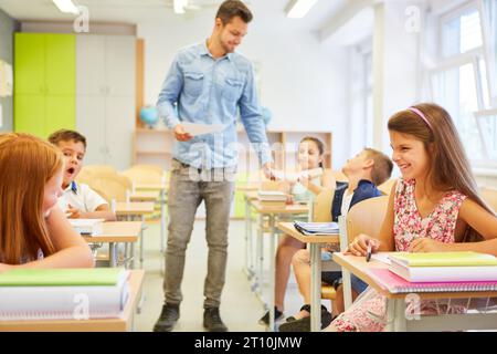Happy female students having fun with teacher while sitting in classroom at school Stock Photo