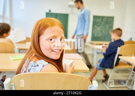 Portrait of smiling redhead female student sitting in classroom Stock Photo
