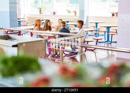 Smiling male and female students sitting together at table during lunch break in canteen Stock Photo