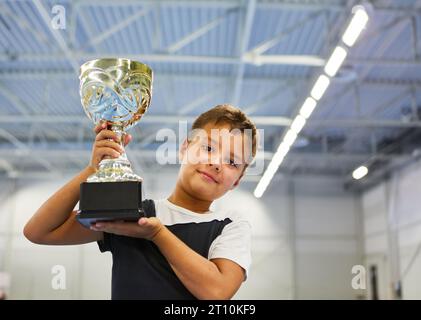 Portrait of schoolboy holding trophy in school gym Stock Photo