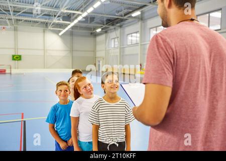 Male teacher talking to elementary students standing in line during gym class Stock Photo