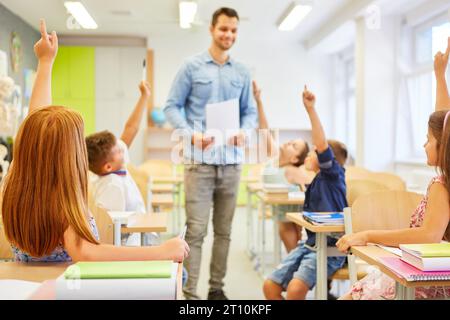 Male and female pupils answering while sitting during lecture in classroom Stock Photo