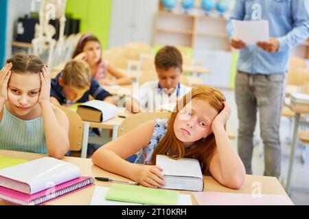 Upset female students sitting together on bench during lecture in classroom Stock Photo
