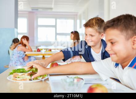 Smiling male students picking up fresh sandwiches during lunch in school at cafeteria Stock Photo