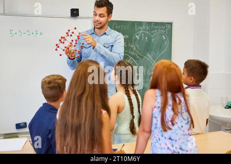 Male teacher explaining molecular structure to elementary students in classroom Stock Photo