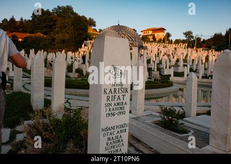 A single soldier's tombstone stands resolute in the soft glow of sunset, a poignant tribute to bravery and sacrifice in Sarajevo's hallowed grounds. Stock Photo