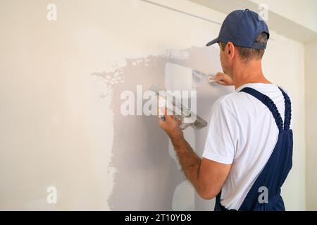 Professional home painter repairing holes and cracks with plaster. Stock Photo