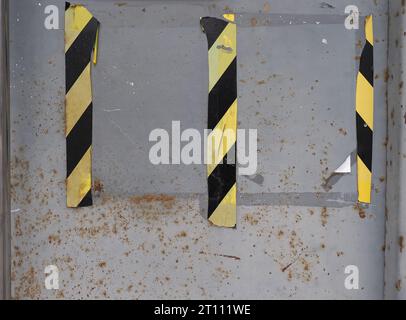 grey metal texture with black yellow striped tape useful as a background Stock Photo