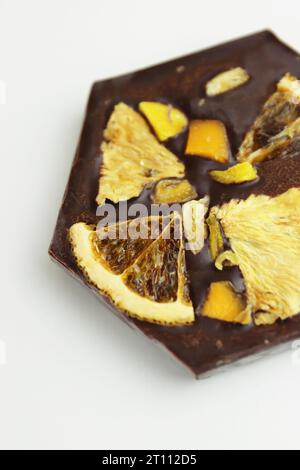 Handmade dark chocolate bar with a dried fruit topping - slices of orange, mango, pineapple. Homemade Chocolate bark in shape of honeycomb. Top view. Stock Photo