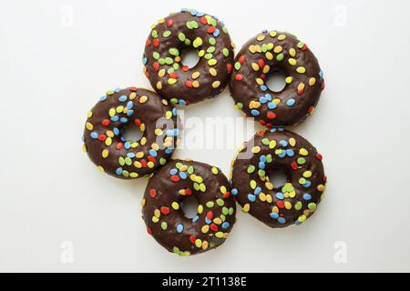 A set of doughnuts glazed with chocolate and colorful smarties. Five donuts isolated on a white background. Side view. Copy space Stock Photo