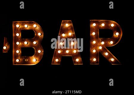 Bar signboard. Inscription from large metal letters decorated with glowing light bulbs Stock Photo